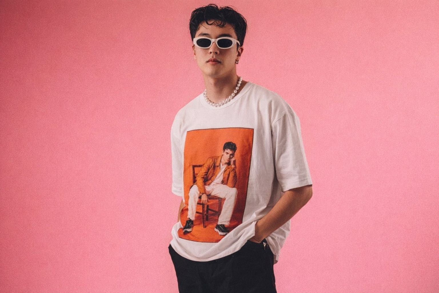 Jeune homme au style urbain portant un t-shirt graphique et des lunettes rétro.